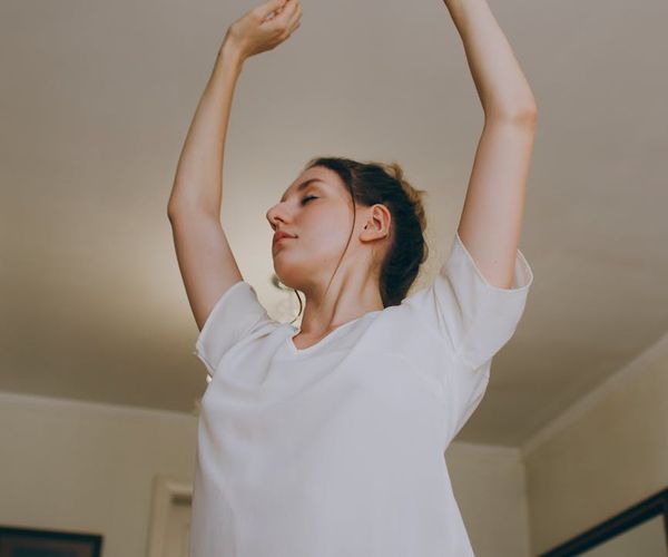 Person stretching peacefully in a bright, minimalist space.